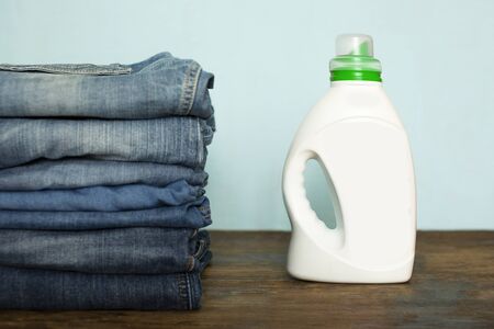Jeans trousers stack on rustic wooden background with cleanser. The concept of cleanliness and...