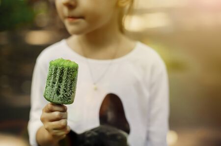 Toddler girl eating green ice-cream in parkの写真素材