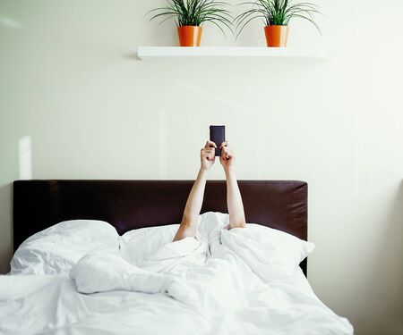 Morning phone in bed, after waking up, immediately check the phoneの写真素材
