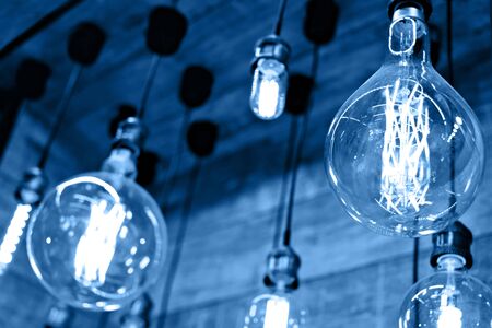 Decorative antique edison style light bulbs against wooden background, blue colorの写真素材