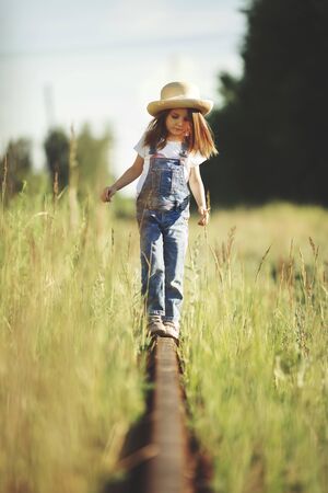 A child plays in the grass. Walk in the tall grass along the old railway tracks, rural summer conceptの写真素材