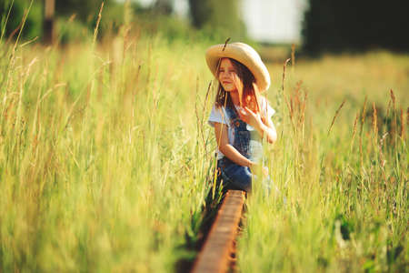 A child plays in the grass. Walk in the tall grass along the old railway tracks, rural summer conceptの写真素材