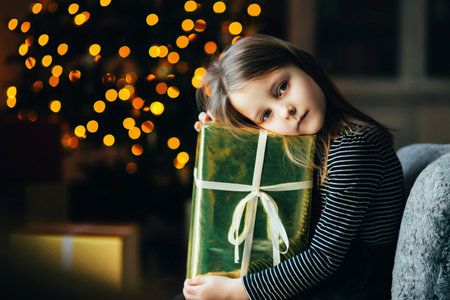 The child in front of the Christmas tree, cozy warm winter evening at home, in waiting for the new...
