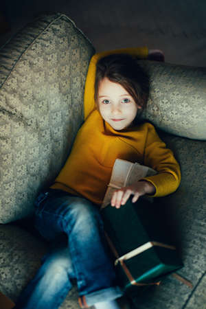 Funny girl with a gift, cozy warm winter evening at home, in waiting for the new yearの写真素材