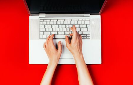 Work from home, online businesses from home office, woman typing on laptop, top view red backgroundの写真素材