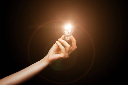 A light bulb in a womans hand on back background