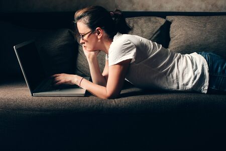 Remote work from house, woman works from home lying on the couch. Social lonelinessの写真素材