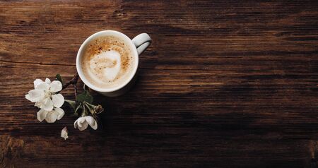 Cup of coffee and blooming apple tree on a wooden table