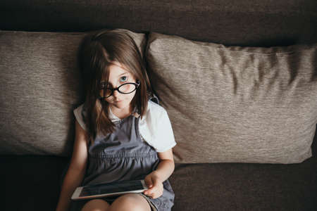 A girl watches a lesson at home on a tablet, remote learning during quarantine, the beginning of...