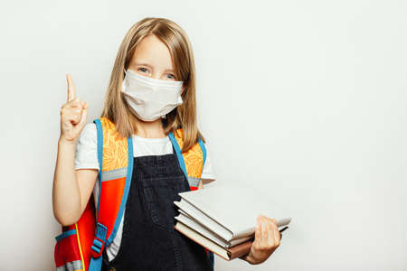 A child in a medical mask prepares for school, the beginning of the school year during a pandemic
