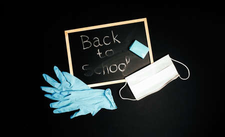 Back to school chalk board, writing in chalk on a black chalkboard medical gloves and medical mask...