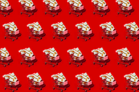 Shopping cart with new Year gifts on red background pattern