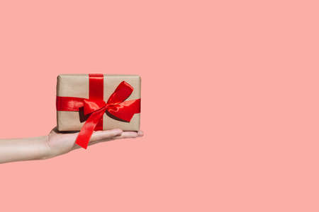 A woman's hand holds a gift with a red bow, the concept of New Year 2021