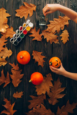 Child paints pumpkins for Halloween. Halloween holiday and family lifestyle background.の写真素材