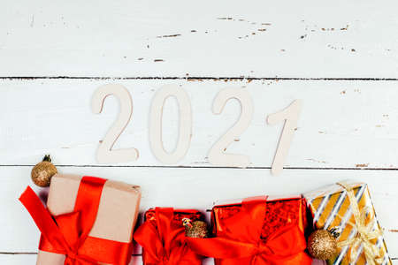 2021 figures New Year and gifts with red ribbon on withe wooden backgroundの写真素材