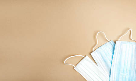 Three medical masks on a beige background, view from above