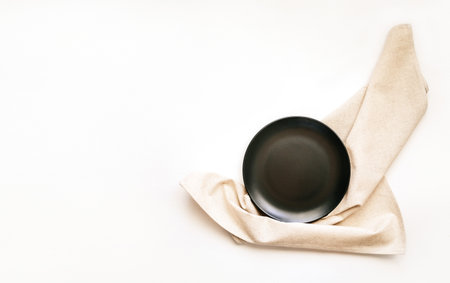 Empty gray plate on a napkin on white wooden background, top view flat layの写真素材