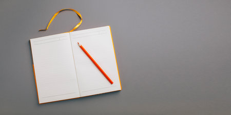 Open yellow diary on a gray background and pen, flat layの写真素材