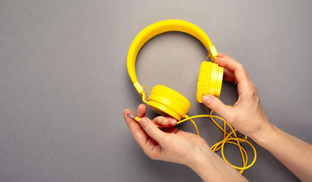 Women's hands hold yellow headphones, top viewの写真素材