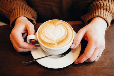 Girl working on a smartphone in a cafe, hands and coffee close-upの写真素材