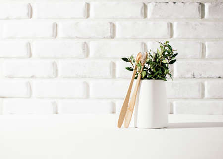 Bamboo toothbrushes on table with green branches, health conceptの写真素材