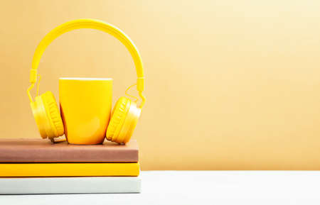 Yellow cup and books with modern headphones. Education business conceptの写真素材