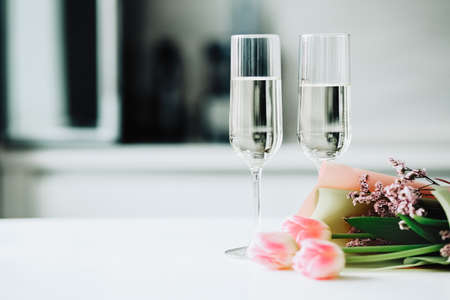 Two glasses and a tulips bouquet on a white tableの写真素材