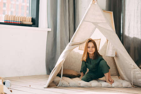 Girl reads a book in a children's hut at home.の写真素材