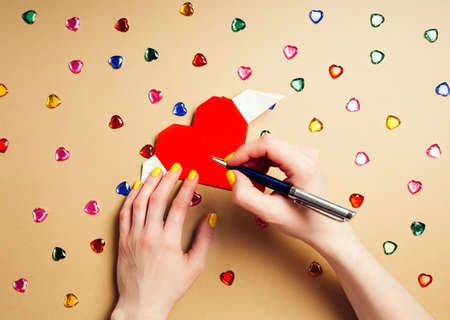 Woman writes a letter on Valentines Day on paper heart origamiの写真素材