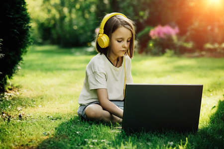 The girl behind the computer in nature, remote learning
