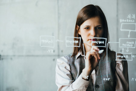 A woman writes with a white marker on a transparent board, user experience designerの写真素材