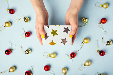 A woman holds a gift in her hands on blue background, New Year conceptの写真素材
