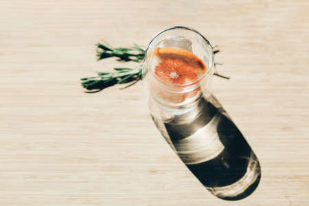 Refreshing cool drink with orange in the sun on a wooden backgroundの写真素材