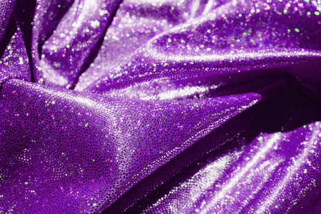 Shiny pleated fabric purple color top view and defocus