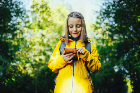 Girl in the woods with a backpack, weekend hike in the woods. Phone navigation on the goの写真素材
