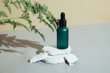 Glass dropper bottle with black lid on pedestalの写真素材