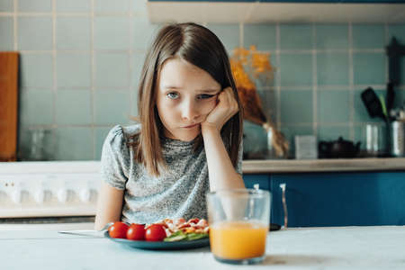 A girl has breakfast in the kitchen, difficulty feeding the childの写真素材
