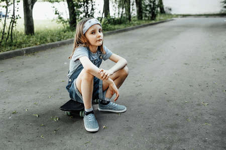 A girl learns to ride a skateboard in the parkの写真素材