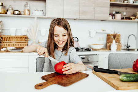 A girl cuts vegetables for a salad, healthy food and vitaminsの写真素材