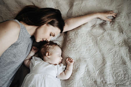 Baby sleeps with mother on the bedの写真素材