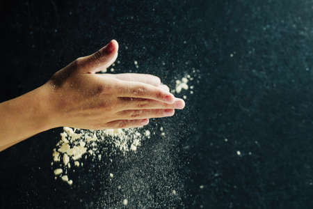 Child preparing pizza dough and clapping flour with hands, home food conceptの写真素材