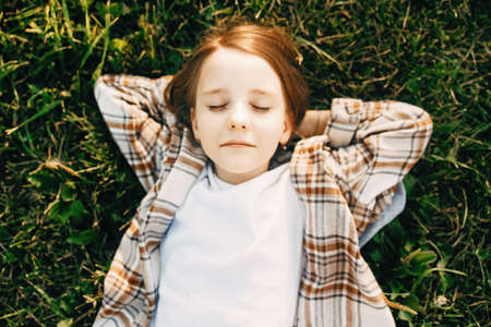 Girl with closed eyes lies on the grass, top viewの写真素材