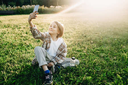A girl takes pictures on her phone in the park, young blogger