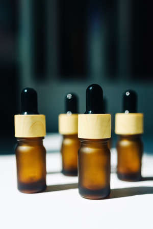 Amber bottle with serum or essential oil. Background with daylight and bottle shadows.