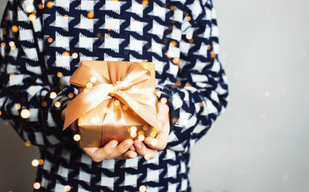 A girl holds a Christmas gift in her handsの写真素材