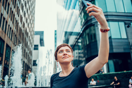 A young woman with a phone in the city, outdoors in the summer in the city centerの写真素材