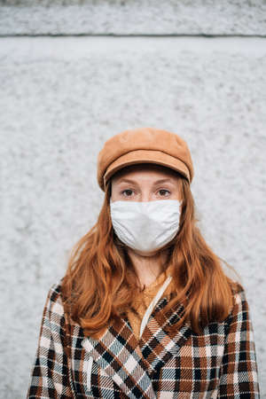 A girl in a protective mask stands near the wallの写真素材