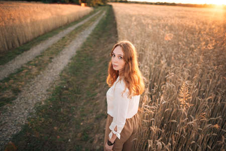 red-haired girl standing in a wheat fieldの写真素材