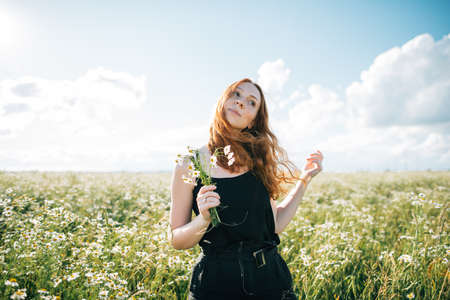 redhead girl in chamomile field