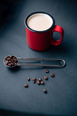 red cup withe coffee and silver spoon with coffee beansの写真素材